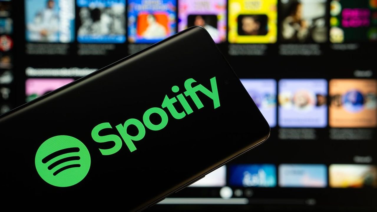 Dhaka, Bangladesh - 18 March 2025: The logo of the spotify is displayed on a smartphone screen, and the website spotify is visible on a computer screen in the background.